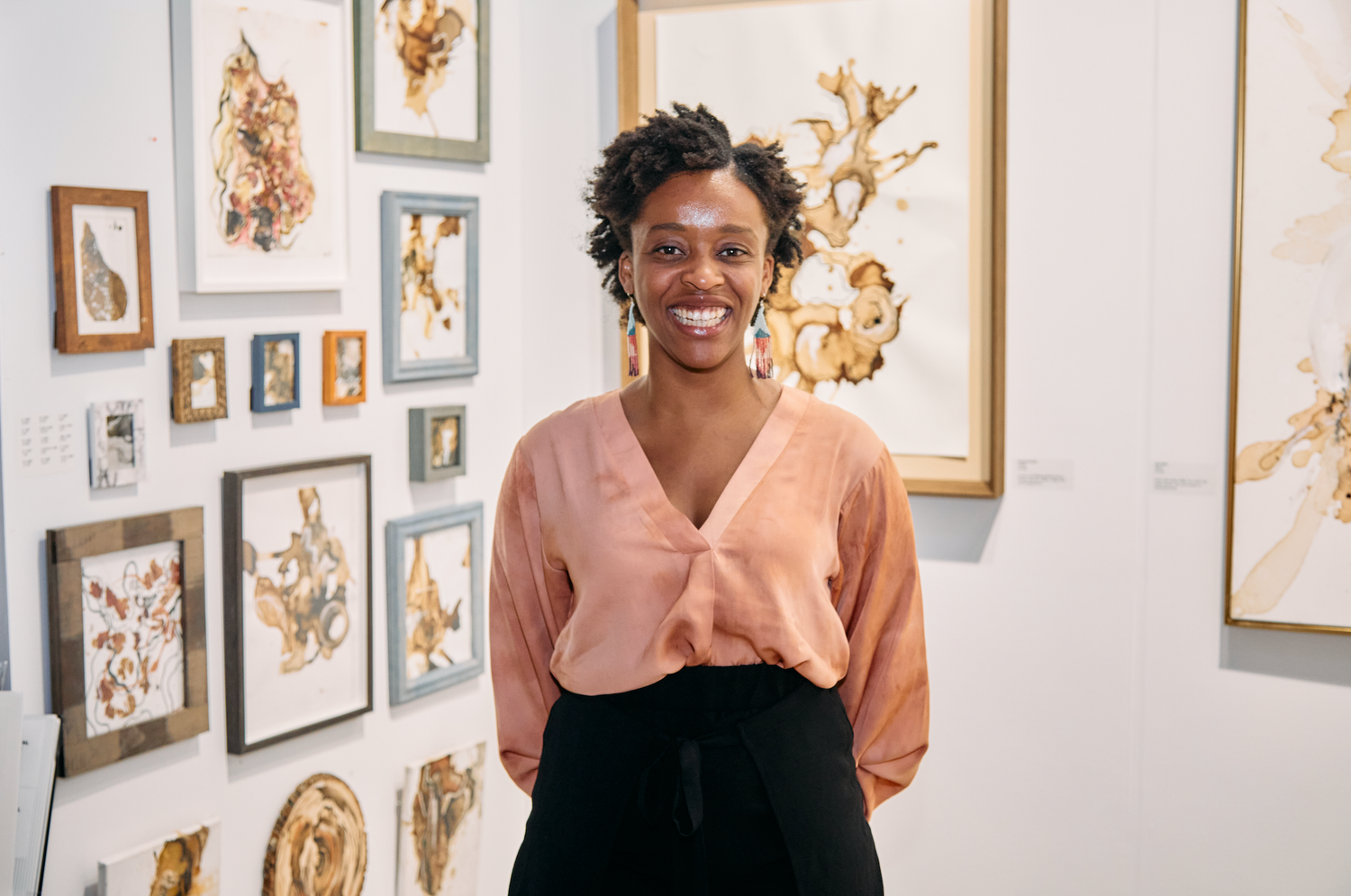 Image of Abena in front of her paintings at The other art fair chicago 2022